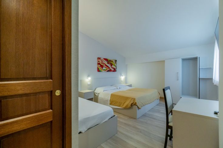 Camera ampia dell'Hotel Bellavista, arredata in modo funzionale e semplice, con gradazioni di colori caldi.