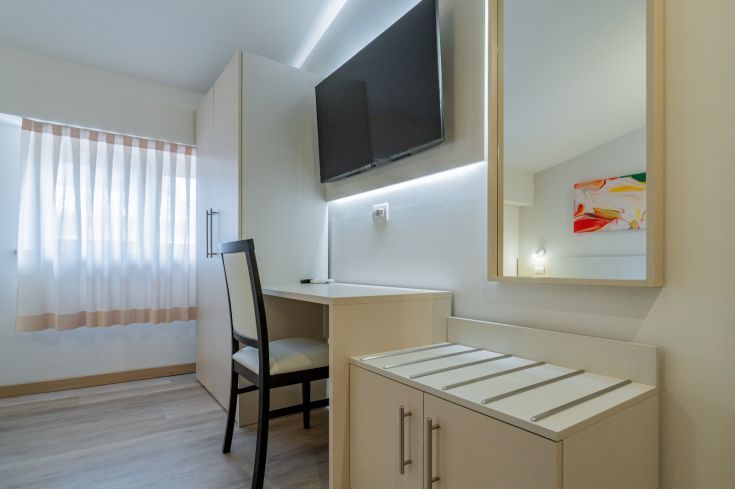 Stanza semplice con TV e scrivania, adatta per un soggiorno tranquillo.