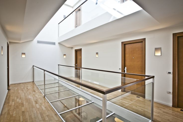 A simple corridor with wooden doors and a glass railing, featuring a bright and clean appearance.
