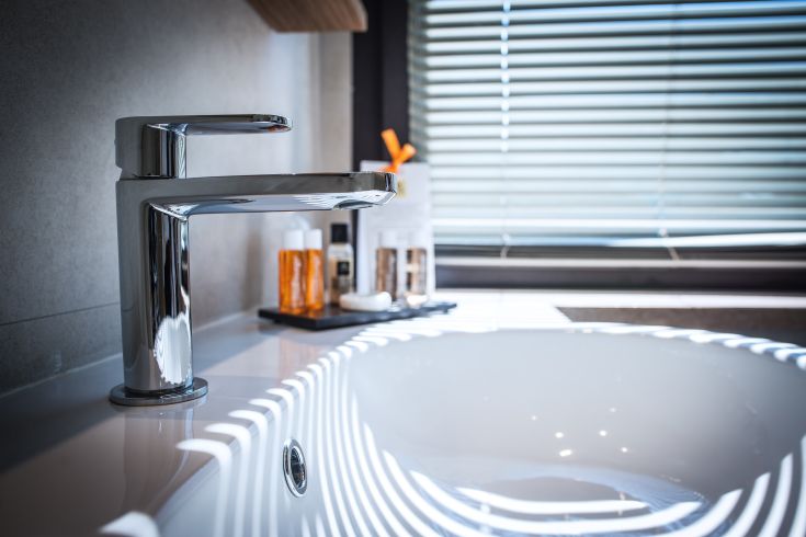 A contemporary sink with a simple designed faucet, enhanced by bathroom accessories in a well-lit environment.