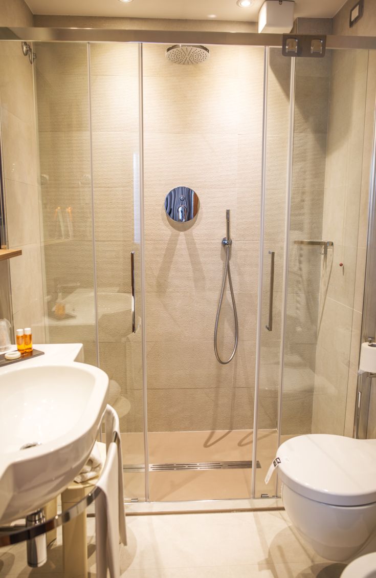 Simple shower with glass walls and practical sink. Clean and functional environment.