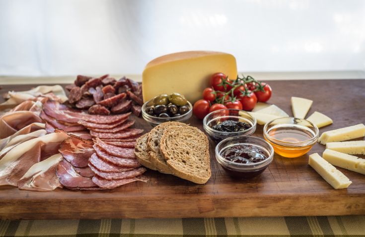 Un tagliere assortito con salumi, formaggi, olive e altre specialità gastronomiche.