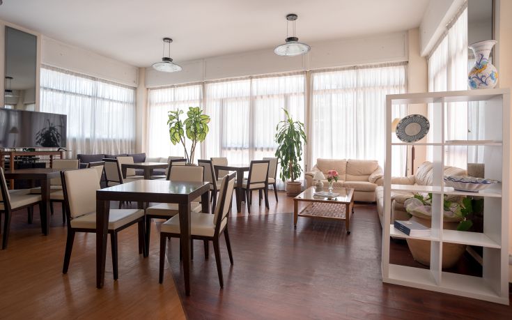 Ambiente illuminato e confortevole con tavoli e sedie, arricchito da piante. Perfetto per incontri e conversazioni.