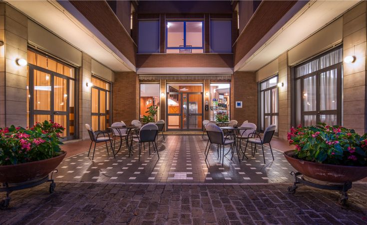 Spazio esterno ben curato con tavoli e piante, adatto per momenti di relax in un hotel.