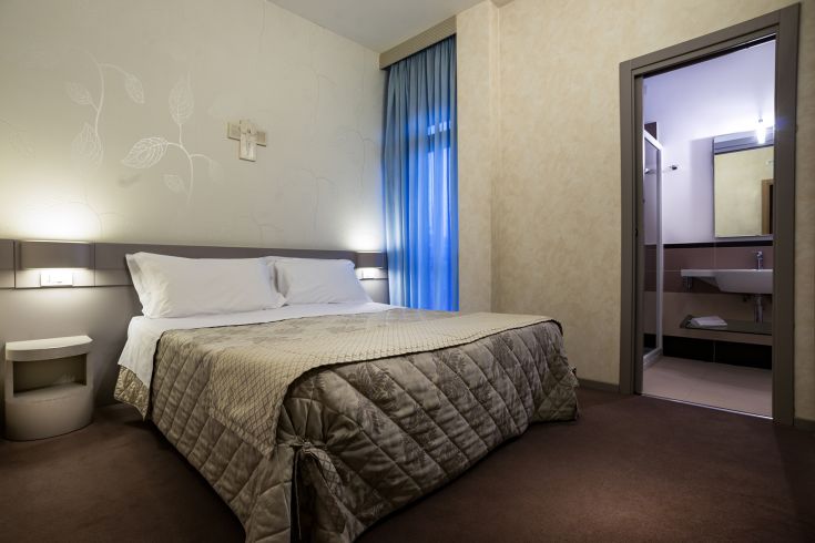 Camera semplice con un letto matrimoniale, dettagli sobri e buona illuminazione naturale.