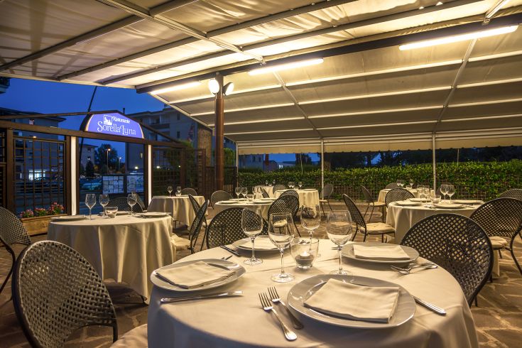 Ristorante all'aperto con tavoli sistemati in modo semplice e un'atmosfera rilassata.