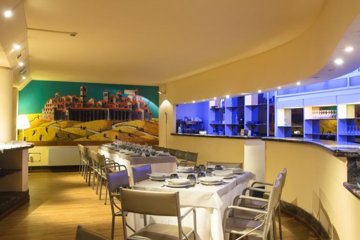 Ristorante raffinato con tavoli apparecchiati e un grande murale sul fondo.