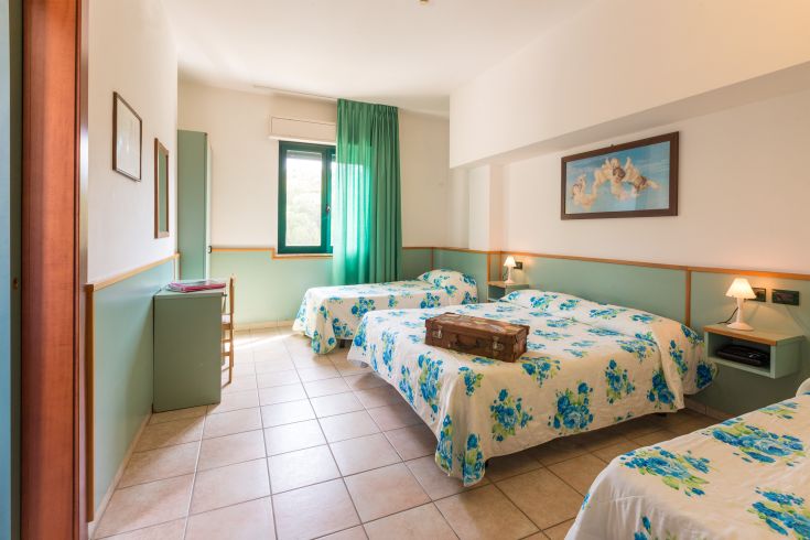 Camera ampia e luminosa con letti singoli, decorata in modo semplice con fiori freschi.