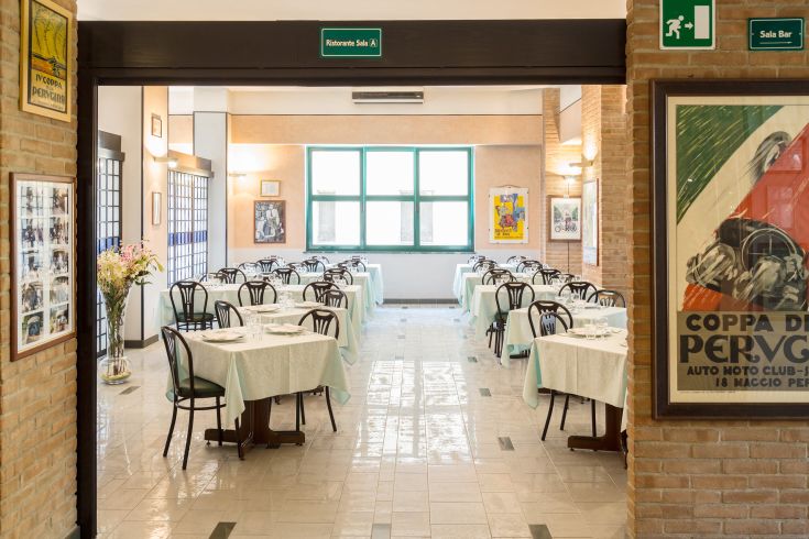 Ristorante con tavoli apparecchiati, ambiente luminoso e arredamento semplice.