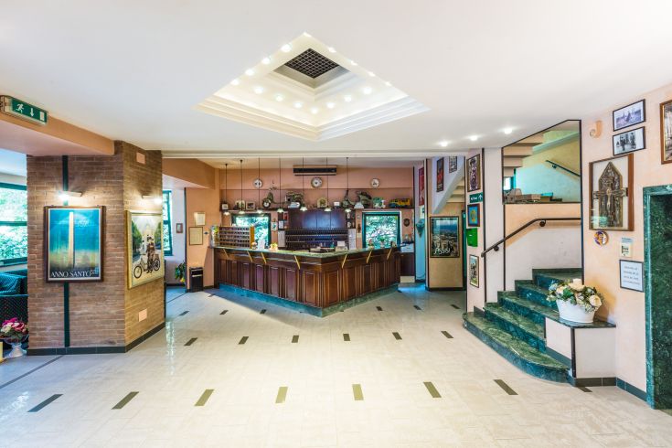 Ingresso dell'Hotel Antonelli, con un bancone reception spazioso e dettagli decorativi semplici.