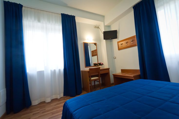 Una camera d'hotel semplice con tende blu e arredi funzionali.