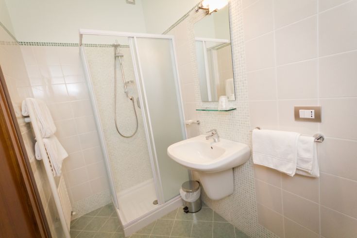 Un bagno semplice con doccia, lavabo e accessori funzionali per l'uso quotidiano.