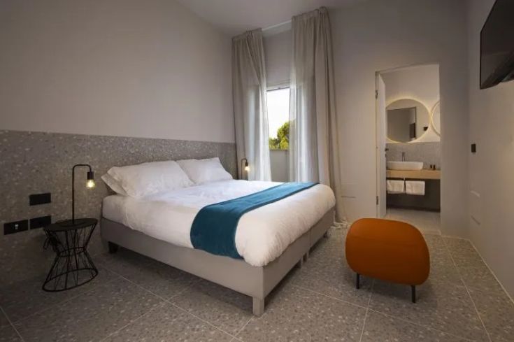 Ein einfaches Zimmer mit einem Doppelbett, minimalistischer Einrichtung, gut beleuchtet und schafft eine gemütliche Atmosphäre.