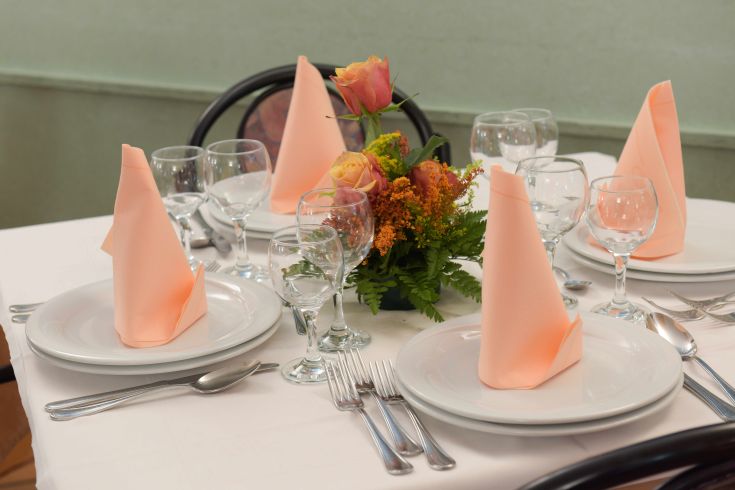 Tavola ben apparecchiata con tovaglioli e un centrotavola di fiori per un evento particolare.