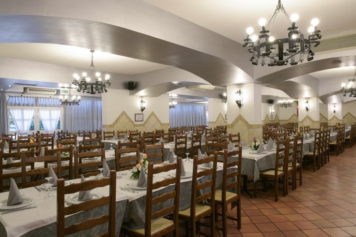 Ristorante ampio con tavoli apparecchiati in modo ordinato, adatto per eventi e cene in compagnia.