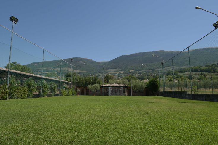 Campo da calcetto circondato da alberi e con panorama sulle montagne.