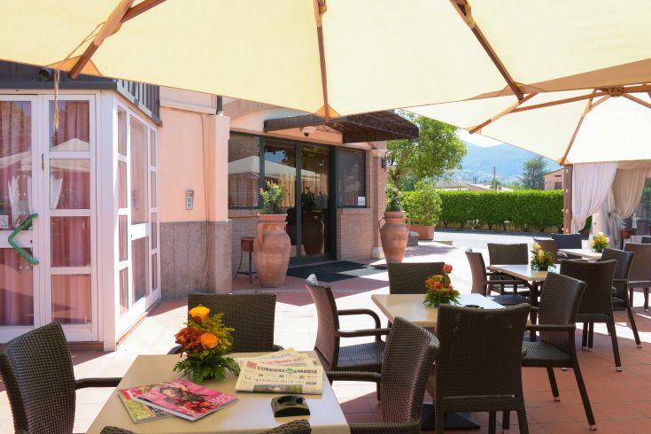 Area esterna dell'Hotel Villa Verde, con tavoli, ombrelloni e un'atmosfera rilassata.