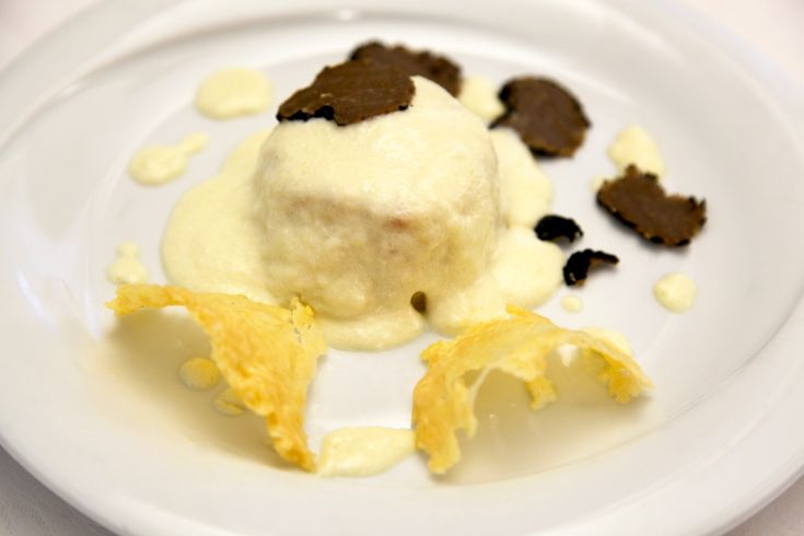 Piatto preparato con crema e tartufo servito su un sottile strato di croccante.