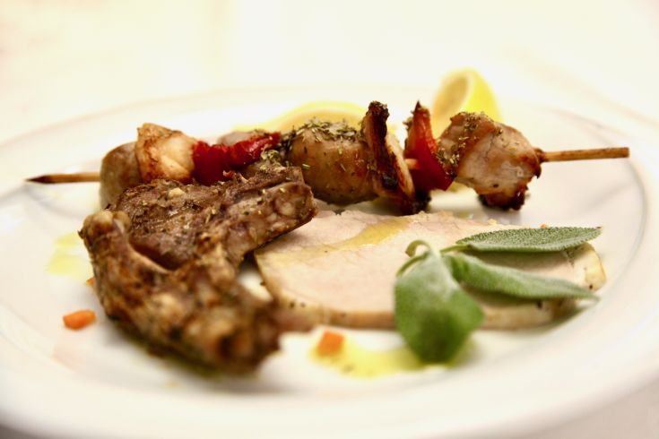 Piatto di carne servito con spiedini e contorni freschi, adatto a chi apprezza i piatti sostanziosi.