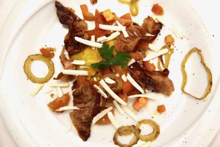 Un piatto appetitoso di carne croccante, pomodori freschi e formaggio, guarnito con prezzemolo.