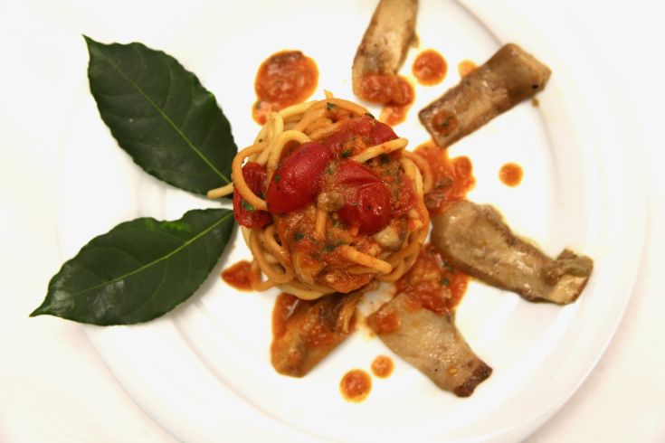 Spaghetti con salsa di pomodoro e funghi, decorati con foglie di alloro.