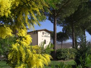 Un hotel situato in un contesto naturale, circondato da fiori gialli e alberi verdi.
