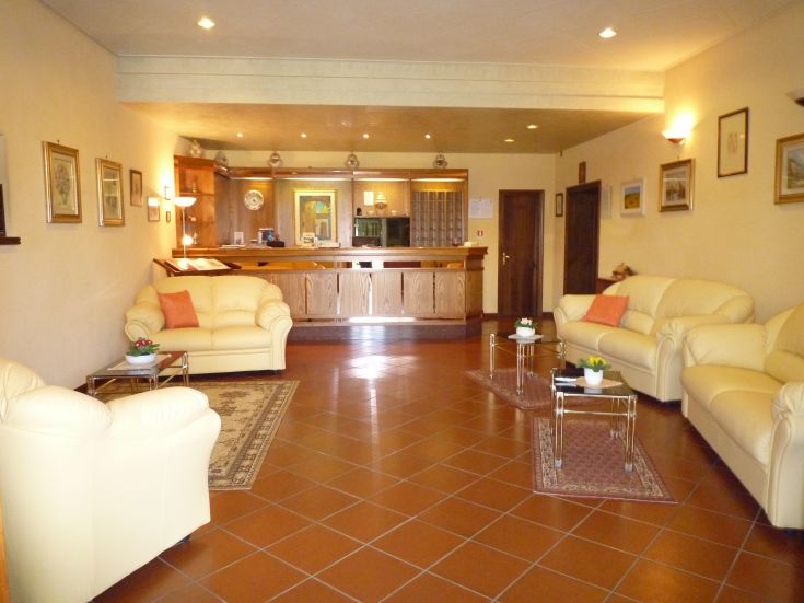 Spaziosa hall dell'hotel decorata con divani chiari e un'accogliente reception in legno.