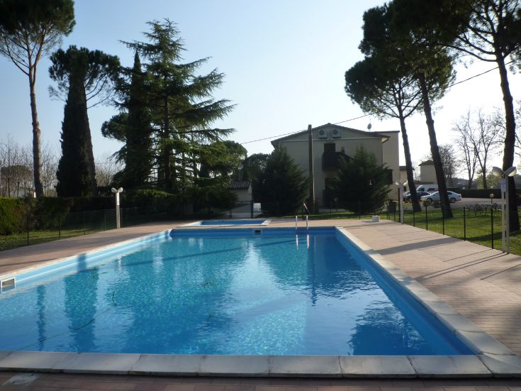 Una piscina ordinata circondata da alberi all'interno del cortile di un hotel.