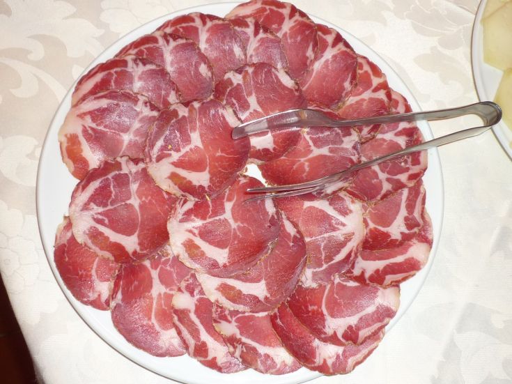 Varie tipologie di affettati disposte su un piatto in modo ordinato.