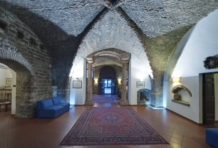 Hall d'un château avec des plafonds voûtés et des meubles anciens restaurés.