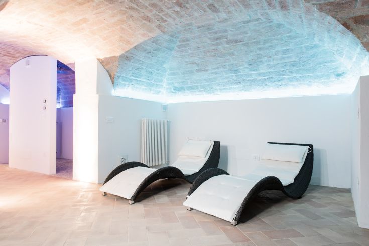 Relax area with comfortable sofas and sunbeds, softly lit, featuring brick walls.
