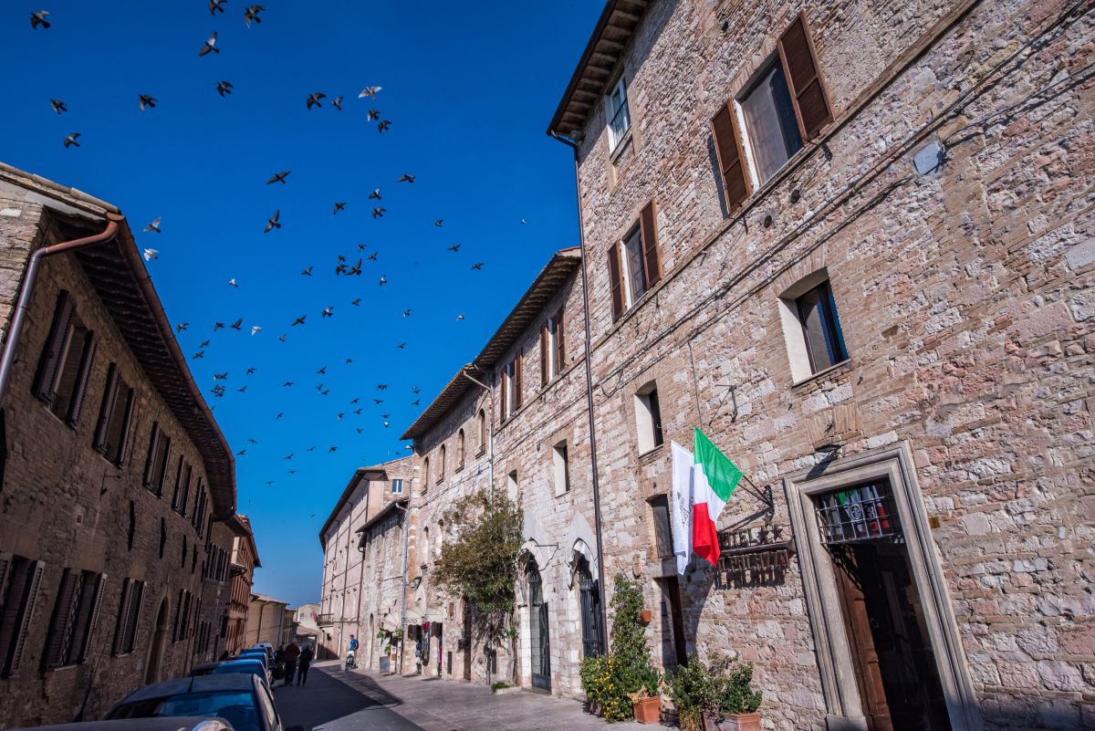 Una scena di un'antica strada in pietra, con un cielo sereno e alcuni uccelli che volano.