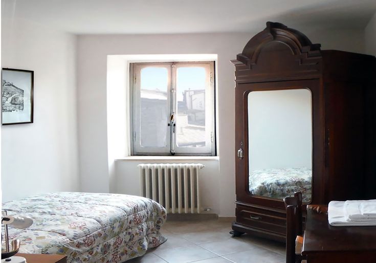Camera accogliente nel centro storico, con arredi semplici e panorama sulla vallata circostante.