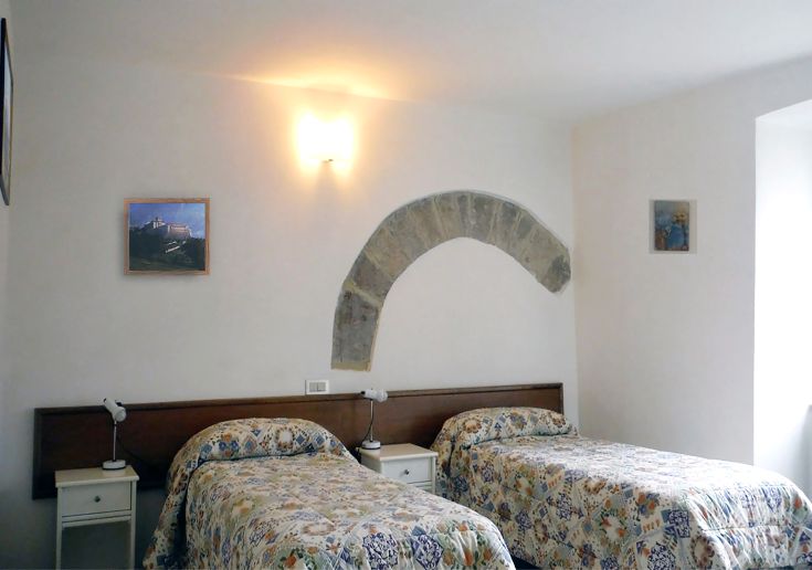 Camera semplice con letti singoli all'interno di un palazzo storico, perfetta per un soggiorno in Umbria.