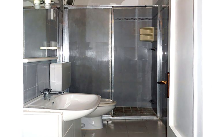 Un bagno contemporaneo con una doccia e sanitari semplici, in un ambiente luminoso e accogliente.