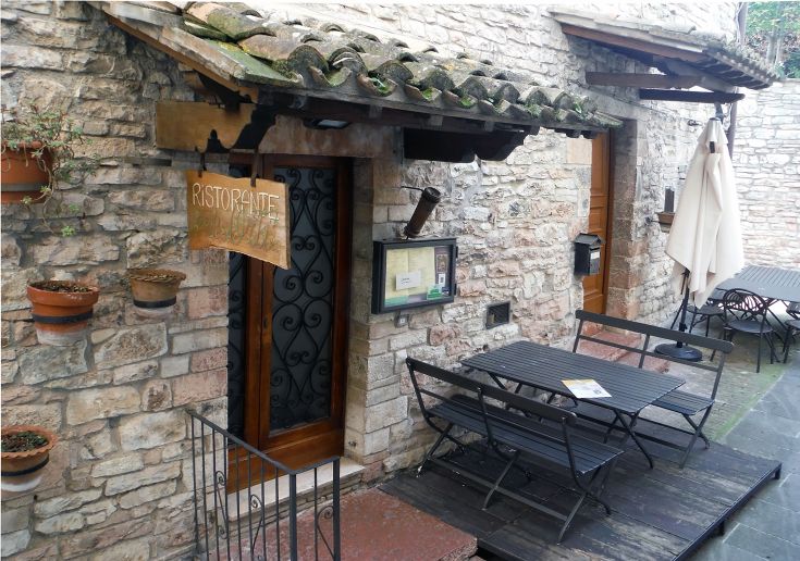 Un ristorante con tavoli all'aperto, situato in un ambiente di carattere medievale.
