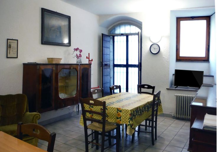 Cucina di un palazzo medievale, dotata di un tavolo in legno e mobili essenziali, illuminata in modo naturale.