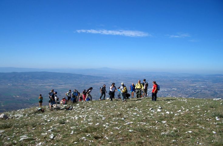 Un gruppo di escursionisti si trova sulla cima di una montagna, ammirando il panorama circostante.