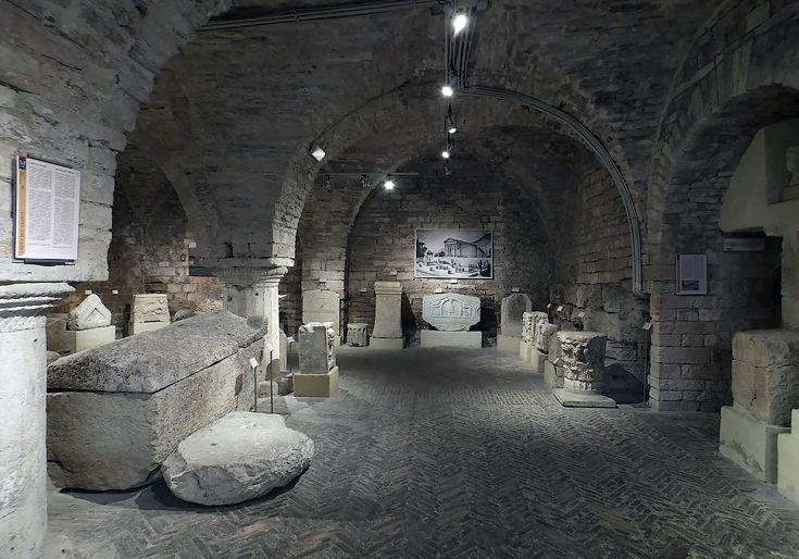 Una mostra di reperti storici in una tranquilla cantina con archi in pietra.