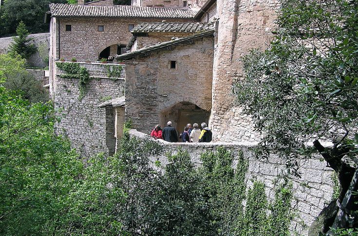 Panorama di Assisi con edifici medievali e aree verdi circostanti.