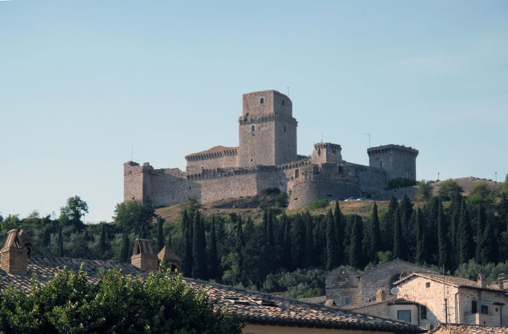 Castello medievale situato su una collina, circondato da alberi e con panorama sulla valle circostante.