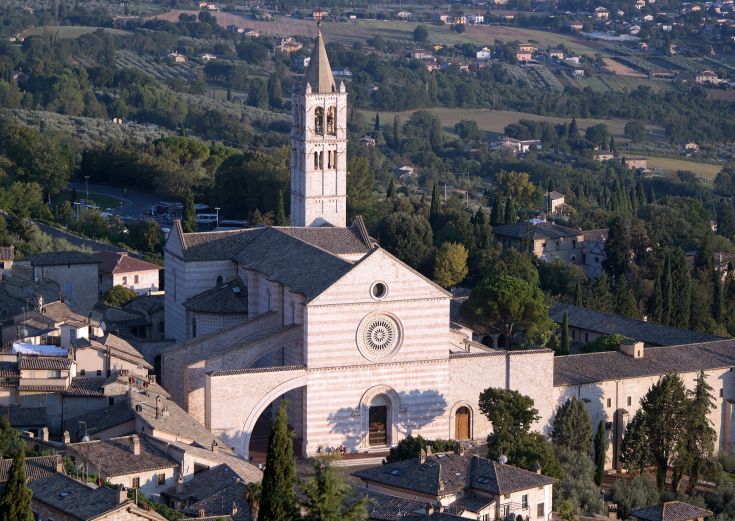 Immagine della Basilica di Assisi con il campanile e i tetti in stile medievale.