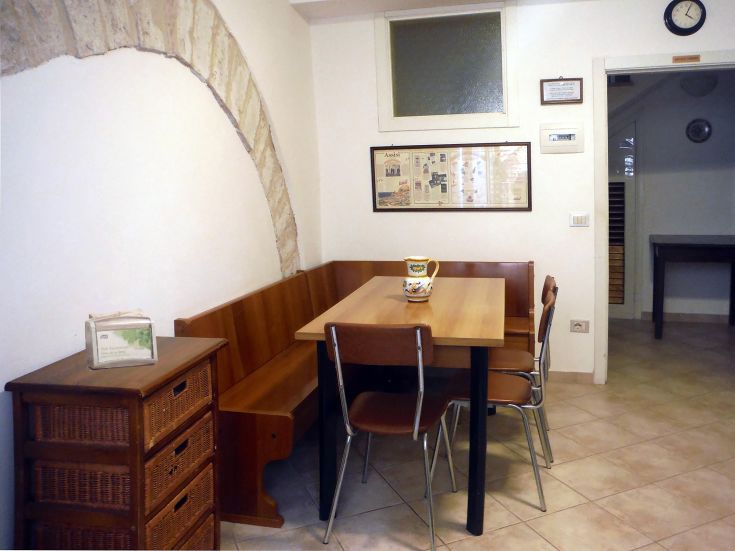 Comparto cucina semplice con tavolo e sedie, adatto per pasti in compagnia di famiglia e amici.