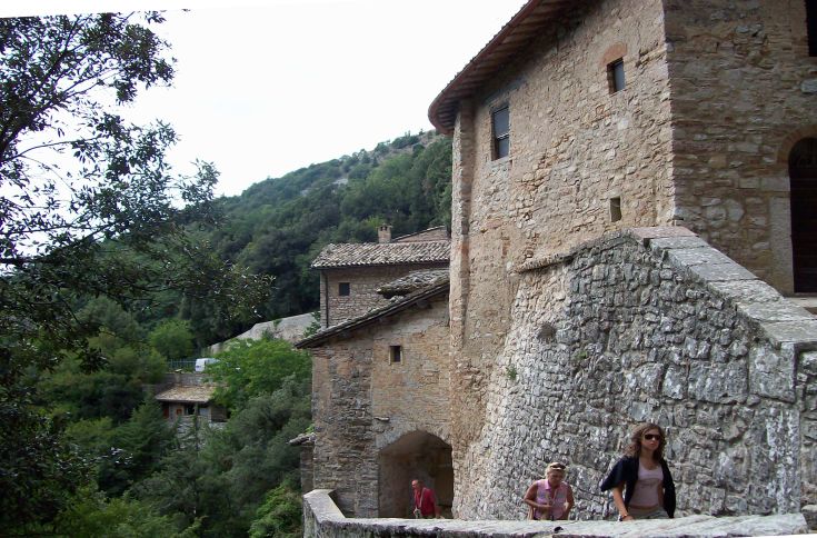 Un palazzo di stile medievale circondato da aree verdi, con visitatori che si muovono nei dintorni.