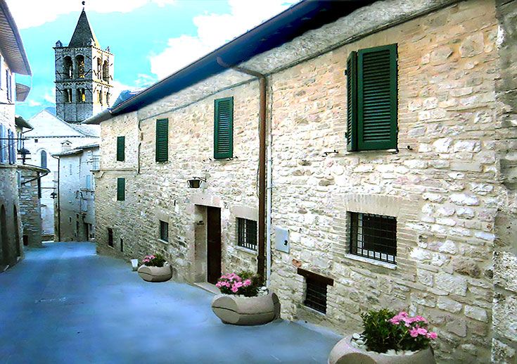 Panorama di Assisi con edifici in pietra e il campanile visibile sullo sfondo.