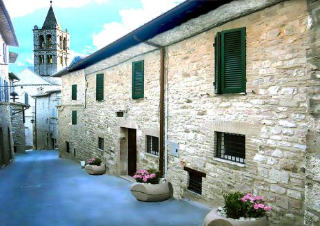 Panorama di Assisi con edifici in pietra e il campanile visibile sullo sfondo.