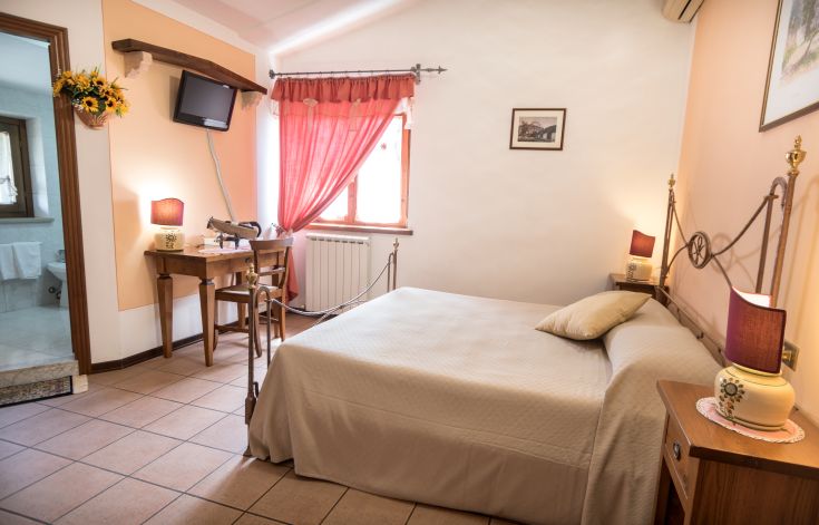 Spazio tranquillo con letti matrimoniali, arredi in legno e luce naturale che filtra dalle finestre.