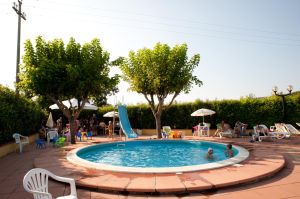 Piscina circondata da vegetazione, adatta per famiglie e momenti di relax. Spazi ampi e aree gioco per bambini.