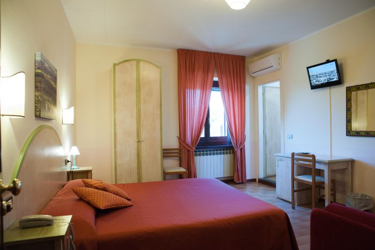 Ambiente confortevole con letto matrimoniale, arredamento essenziale e finestra che consente l'ingresso di luce naturale.