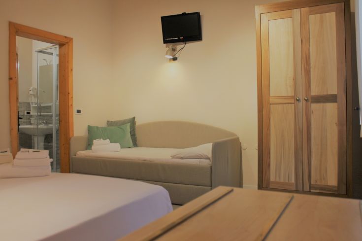 Ampia camera con letti comodi e armadio in legno, adatta per un soggiorno rilassante.